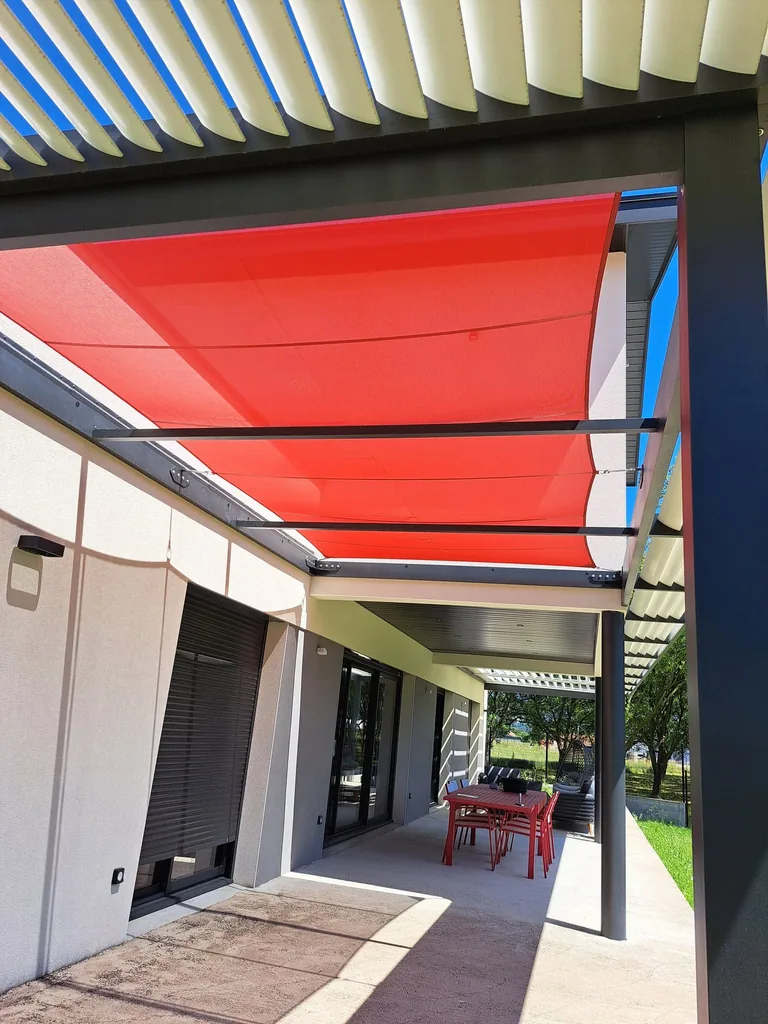Voile d’ombrage rouge vue de dessous, sous les lames orientables crème de la pergola bioclimatique