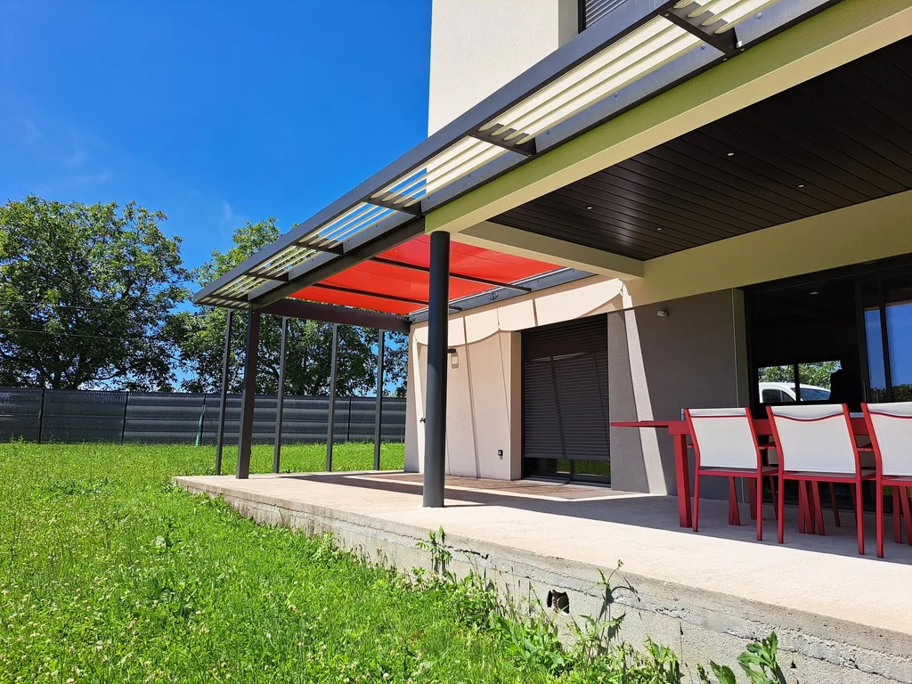 Voile d’ombrage et pergola bioclimatique vues de côté depuis la pelouse