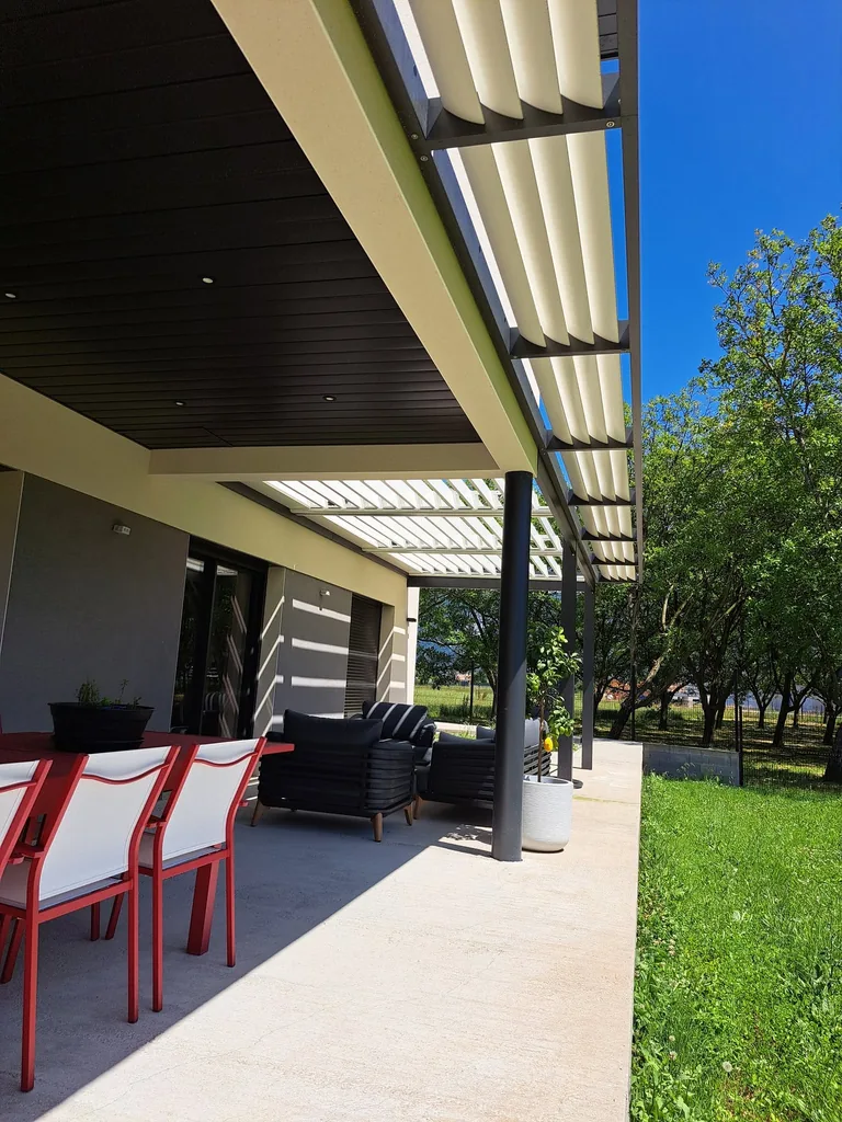 Coin repas installé sur la terrasse sous la pergola bioclimatique